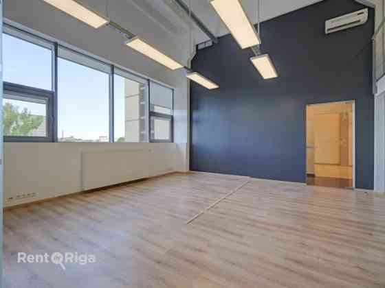 A spacious and bright loft-style office featuring an open-plan workspace and separate private office Рига