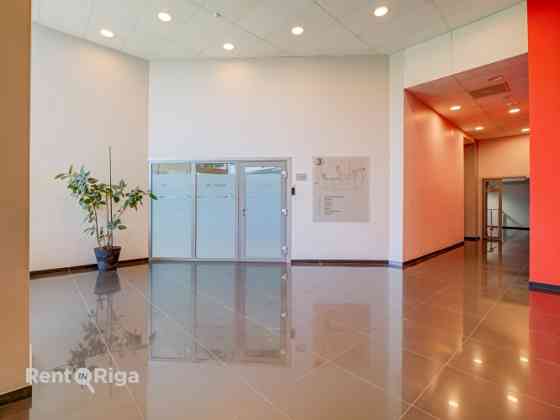 A spacious and bright loft-style office featuring an open-plan workspace and separate private office Рига