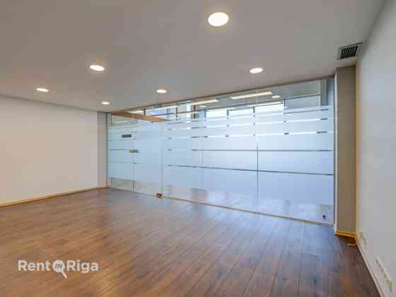 A spacious and bright loft-style office featuring an open-plan workspace and separate private office Рига