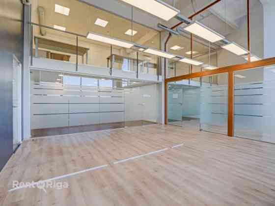 A spacious and bright loft-style office featuring an open-plan workspace and separate private office Рига