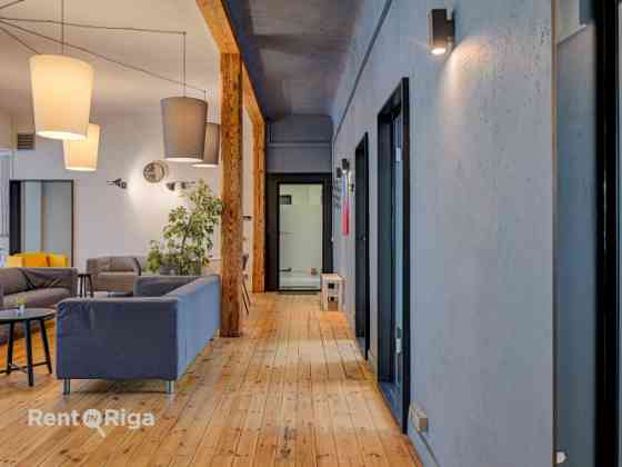 Office with a creative industrial atmosphere  high ceilings, wooden plank floors, exposed wooden bea Рига
